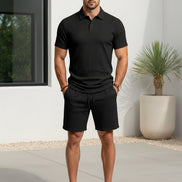 A man wearing a black short-sleeve polo shirt and matching black shorts 