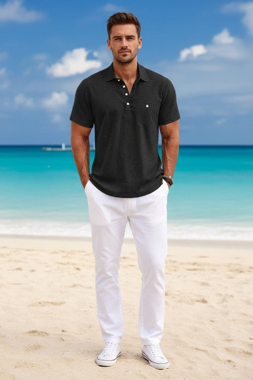 Man wearing a black textured polo shirt with a blurred beach background
