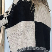 Person wearing a black and white checkered knit sweater against a light background