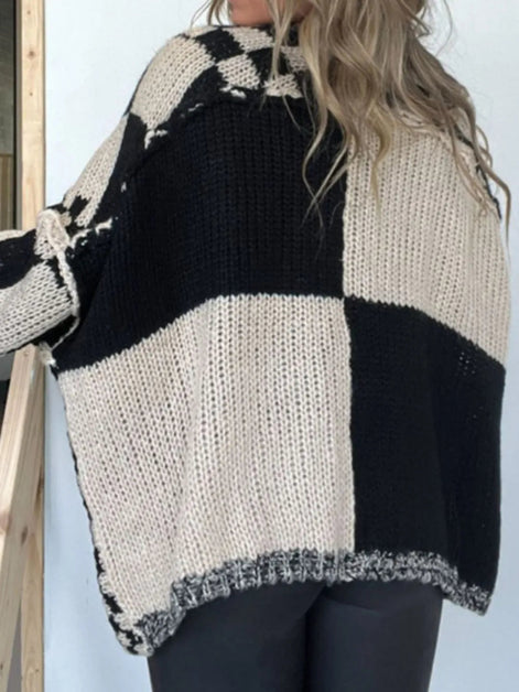 Person wearing a black and white checkered knit sweater against a light background