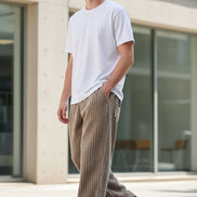 A person wearing loose, ribbed corduroy pants in a taupe-brown color, paired with a white t-shirt 