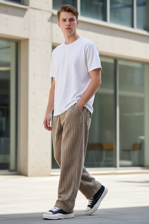A person wearing loose, ribbed corduroy pants in a taupe-brown color, paired with a white t-shirt 