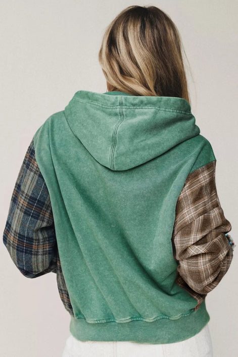 A person shown from the back wearing a hooded sweatshirt with a washed green body and contrasting plaid sleeves i