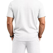 A man viewed from the back wearing a white short-sleeve polo shirt and matching white 