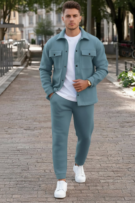 A man wearing a matching dusty blue two-piece tracksuit with a button-up shirt jacket and matching jogger pants, 