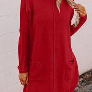 Red sweater dress worn by a person against a white brick wall.