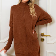 Woman wearing a brown sweater dress standing in front of a white door.