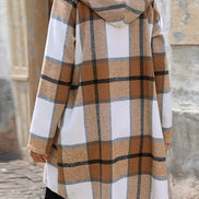 Plaid coat with a hood worn by a person, standing on a stone pavement.