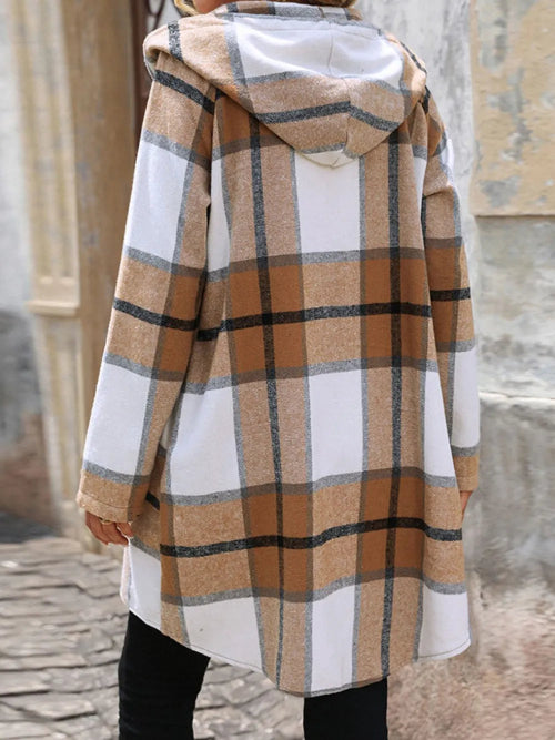 Plaid coat with a hood worn by a person, standing on a stone pavement.