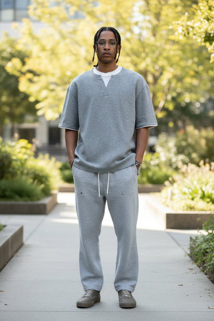 Person wearing a gray V-neck shirt and gray pants on a white background