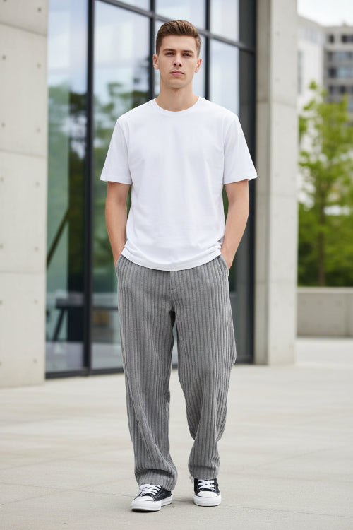 A person wearing gray ribbed corduroy pants with a white t-shirt and black-and-w