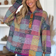 Woman wearing a colorful patchwork hoodie in a home setting