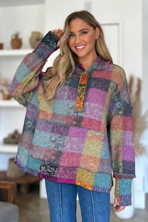 Woman wearing a colorful patchwork hoodie in a home setting