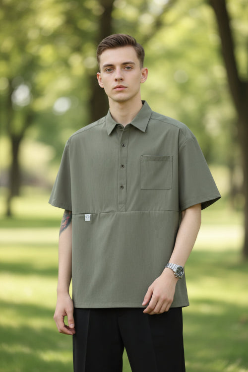 Person wearing a green short-sleeve shirt with a pocket on a white background