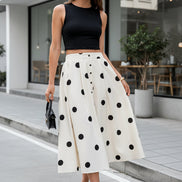 Person wearing a white skirt with black polka dots on a striped pavement.