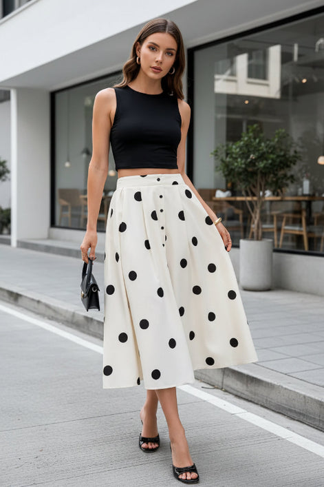 Person wearing a white skirt with black polka dots on a striped pavement.
