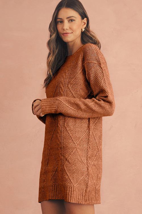 Woman wearing a brown knitted sweater dress against a pink background