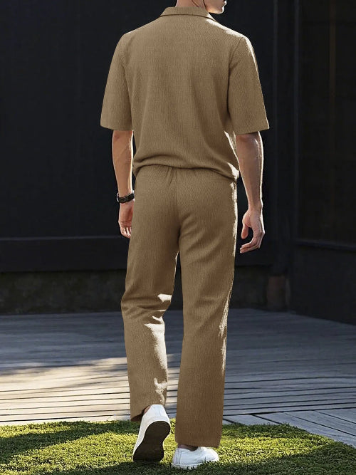 A man viewed from behind wearing a matching tan short-sleeve knit polo shirt and trousers set, 