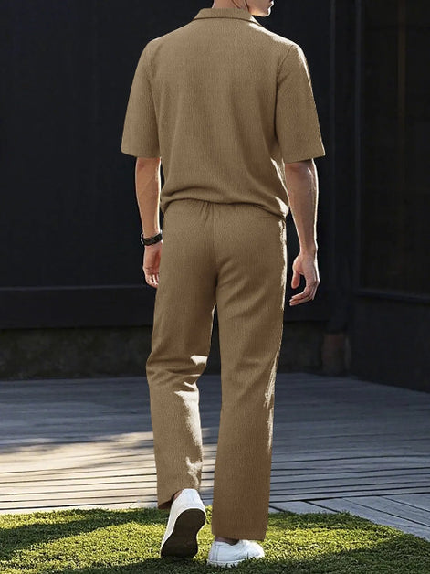 A man viewed from behind wearing a matching tan short-sleeve knit polo shirt and trousers set, 