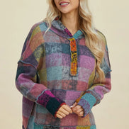 A woman modeling a multicolor patchwork plaid pullover hoodie with a hood, kangaroo pocket, and ribbed cuffs, 