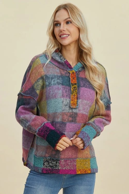 A woman modeling a multicolor patchwork plaid pullover hoodie with a hood, kangaroo pocket, and ribbed cuffs, 