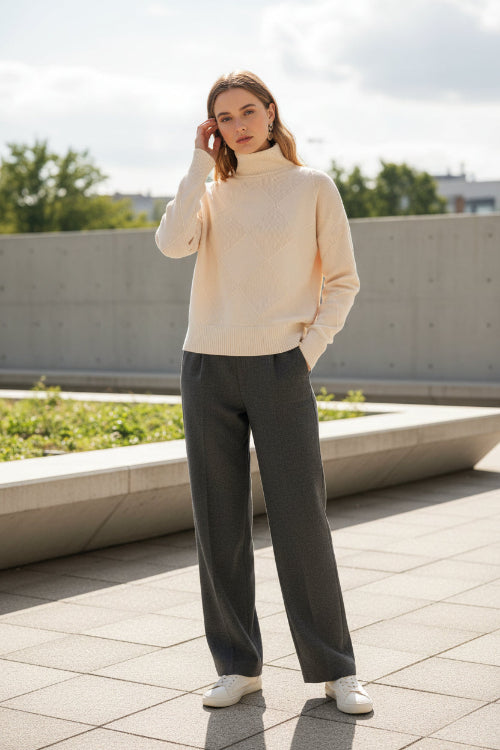 Beige turtleneck sweater worn by a person against a neutral background