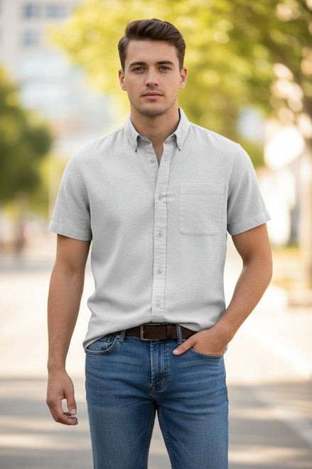 Man wearing a light gray short-sleeve button-up shirt with a white background