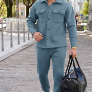 A man wearing a matching dusty blue fleece tracksuit with a button-up shirt and jogger pants, 