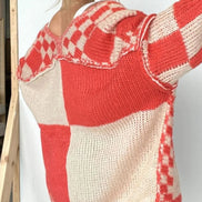 Red and white checkered sweater worn by a person on a plain background