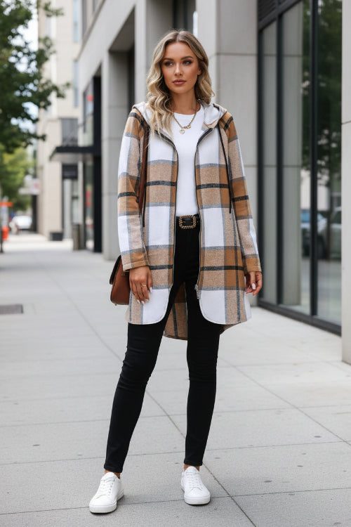 Person wearing a plaid coat holding a coffee cup against a textured wall.