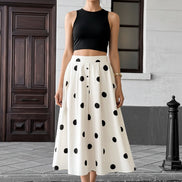 Person wearing a white skirt with black polka dots on a city street.