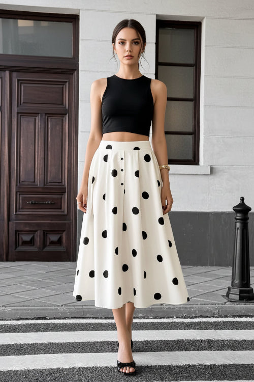 Person wearing a white skirt with black polka dots on a city street.