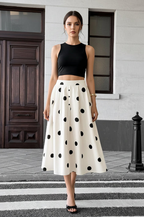 Person wearing a white skirt with black polka dots on a city street.