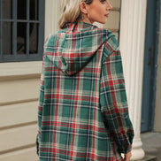 Person wearing a green plaid jacket with a hood outdoors.