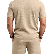 A man viewed from the back wearing a beige short-sleeve polo shirt and matching shorts, 