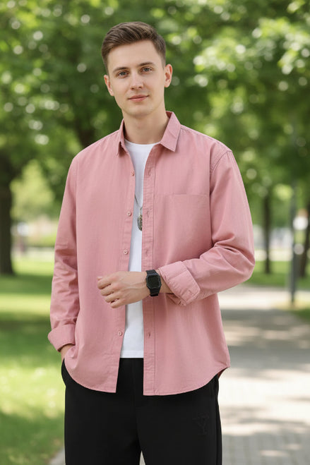 Person wearing a pink button-up shirt over a white t-shirt on a gray background