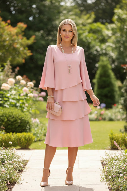 Woman wearing a pink dress with a matching clutch against a white background