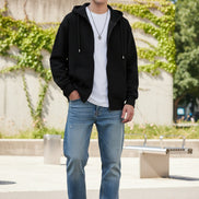 Person wearing a black hoodie over a white shirt on a light gray background