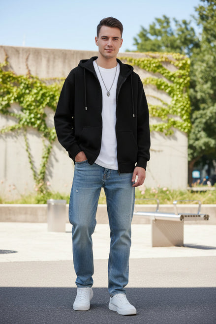 Person wearing a black hoodie over a white shirt on a light gray background