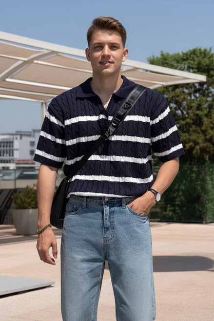 Person wearing a navy and white striped polo shirt with blue jeans outdoors.