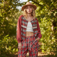 Woman wearing a red plaid shirt, white top, and brown hat against a beige background