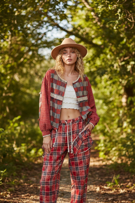 Woman wearing a red plaid shirt, white top, and brown hat against a beige background
