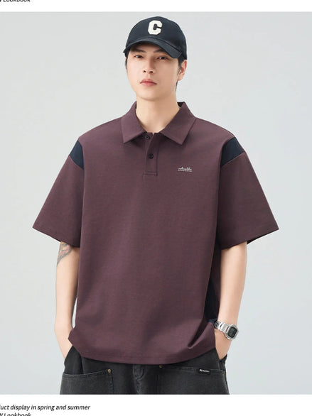 Man wearing a maroon polo shirt with black sleeves and a cap on a light gray background