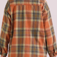 Plaid shirt with orange and green pattern worn by a person on a white background