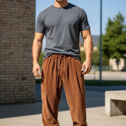 A man wearing brown corduroy jogger pants with a drawstring waist and elastic cuffs, paired with white sneakers, 