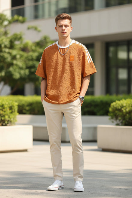 Orange t-shirt with white stripes on sleeves and a patch on chest against a plain background