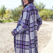 Woman wearing a purple and white checkered coat outdoors.