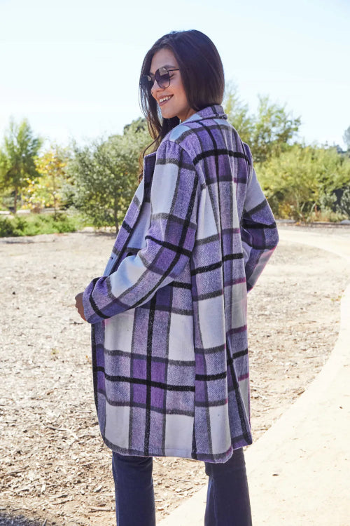 Woman wearing a purple and white checkered coat outdoors.