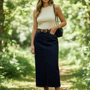 Person wearing a white top and dark blue denim skirt on a wooden floor.