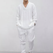 A person wearing a matching white knit lounge set consisting of a long-sleeve V-neck sweater and jogger pants, 